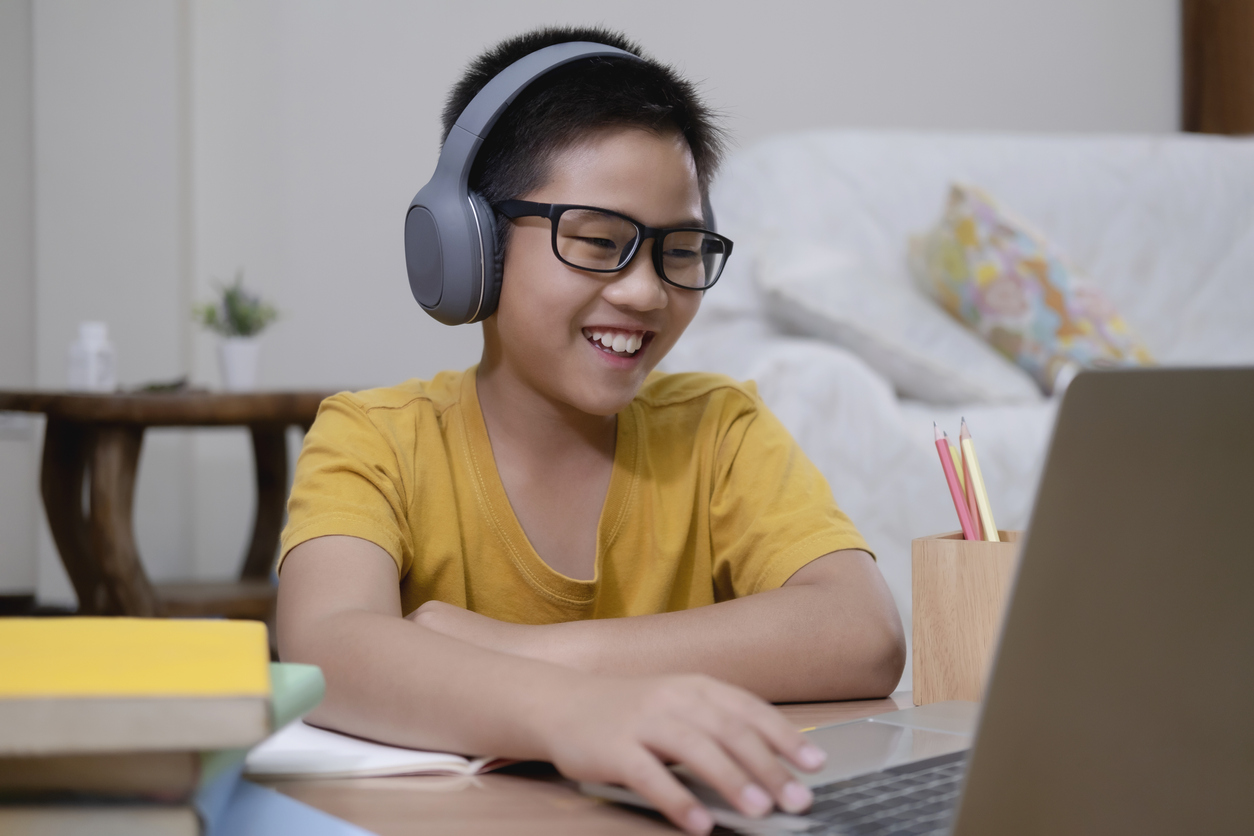Cheerfully boy excited using computer online learning schoolwork. Asian boy enjoy self study with e-learning at home. Online education and self study and homeschooling concept.